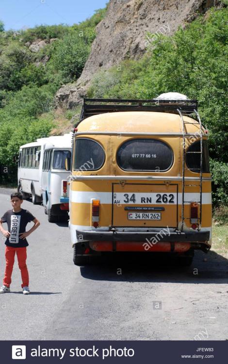 a-small-boy-stands-next-to-an-old-bus-near-geghard-monastery-in-armenia-JFEW83.jpg